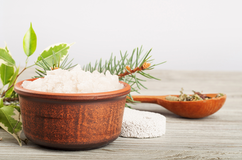 Aromatic bath salt in a clay cup and pumice stone on a wooden background.