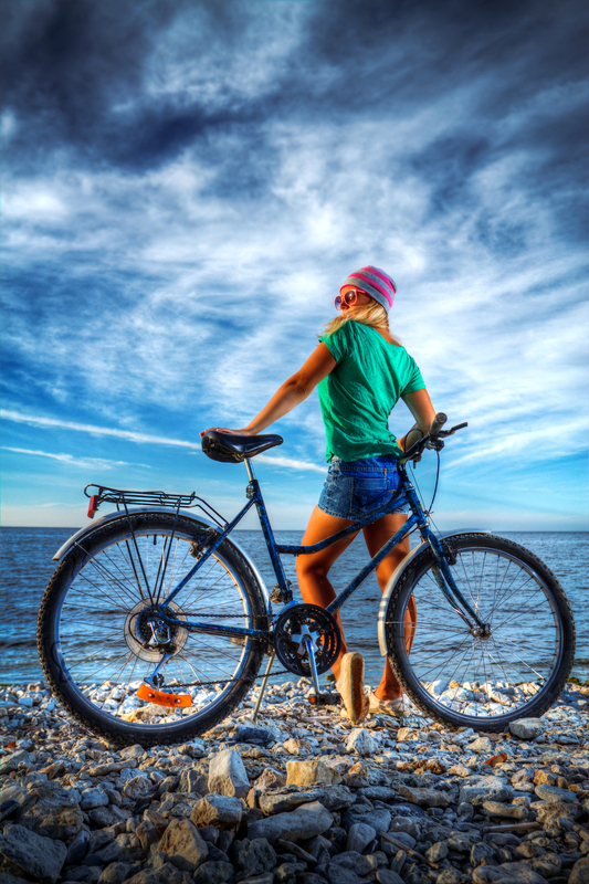 girl with a bicycle on the beach by the sea